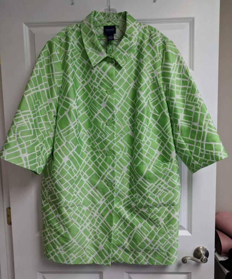 white and green raincoat hangs on door